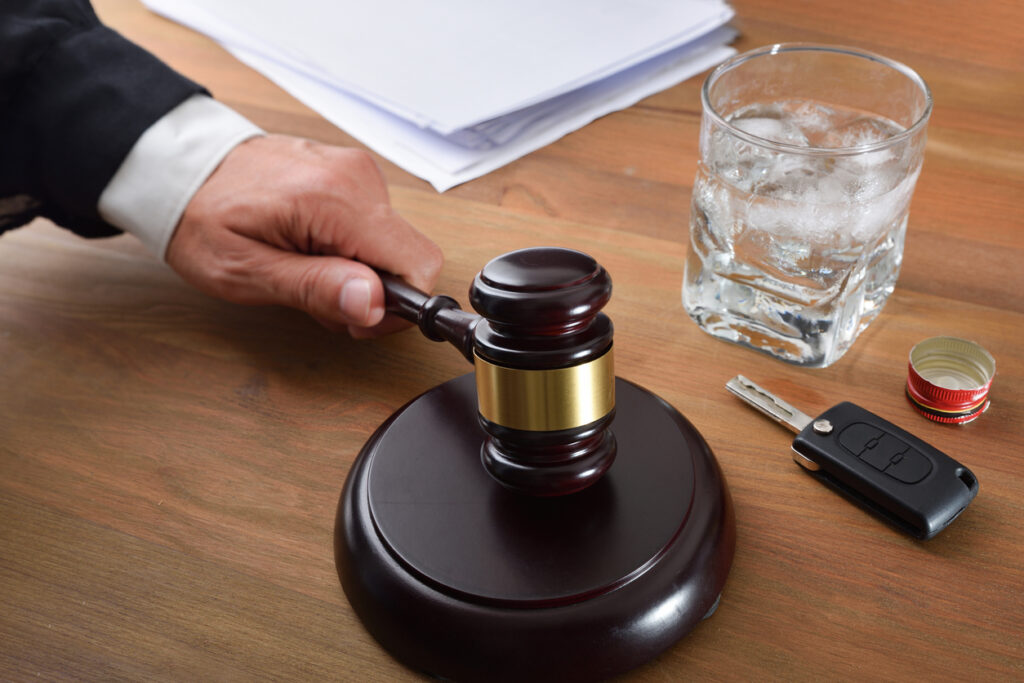 judge's hand hitting a gavel next to an alcoholic drink