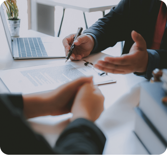video A person holding a pen discussing a document with another person at a table in an office setting.